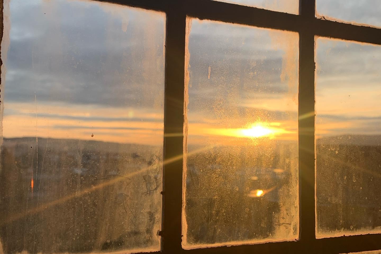 Blick durch ein Fenster auf einen Sonnenuntergang